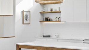 Une cuisine moderne avec des meubles blancs, une table à manger en bois et des tabourets de bar.