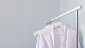 Une serviette blanche est suspendue à un étendoir en métal, devant un mur uni.