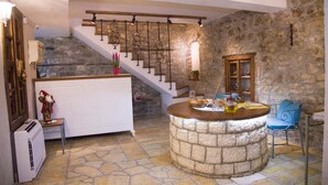 A stone-floored living area with a central bar, a staircase with wrought iron railings, and a rustic wooden door. - Villa 4 Bed & Breakfast (Berat)