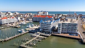 Ein Yachthafen mit vertäuten Booten, ein großes Hotel mit mehreren Balkonen und freier Meersicht.