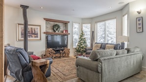 Una sala de estar con chimenea, televisor, sofá y un árbol de Navidad.
