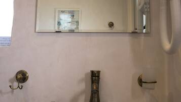 Een badkamer met een marmeren wastafel, een spiegel, een zeepdispenser en een toilet.