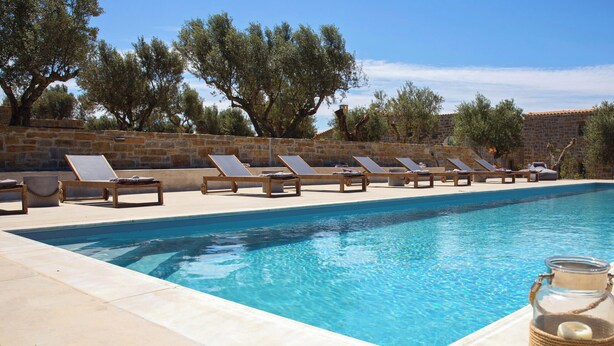 Ein Swimmingpool mit Liegestühlen und einem Glas auf dem Rand.
