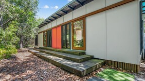 A modern house with a wooden deck and a red door. - 16 Ibis Court - Rainbow Shores. Wifi. Pool. Quick walk to beach (RAINBOW BEACH)