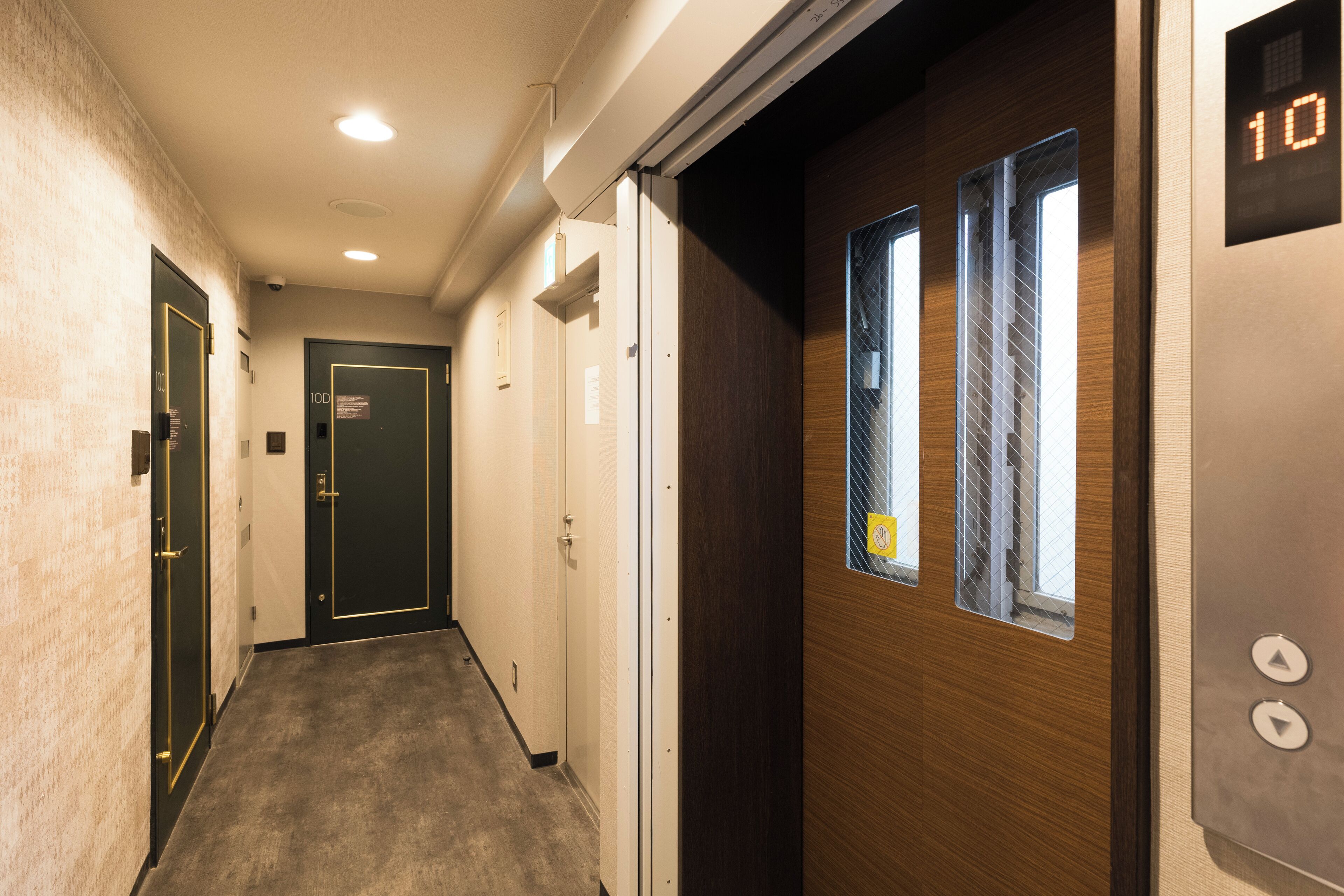A hallway with doors, a wooden door with a window, and a digital display showing the number 10.