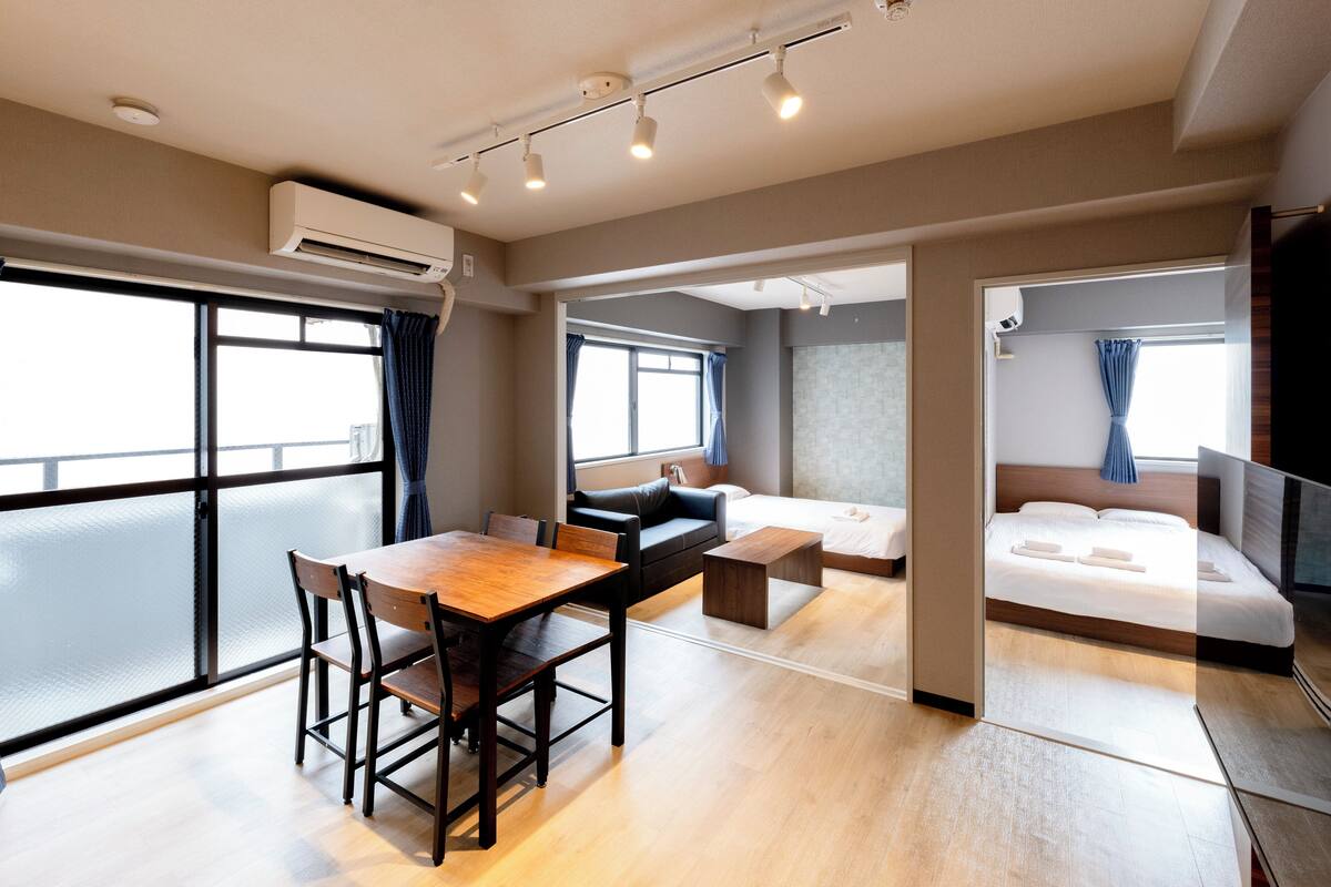 Una habitación de hotel moderna con una mesa de comedor de madera, un sofá, una cama y un televisor.