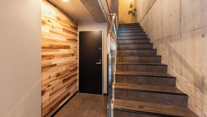 A modern staircase with a wooden wall on one side and a concrete wall on the other.