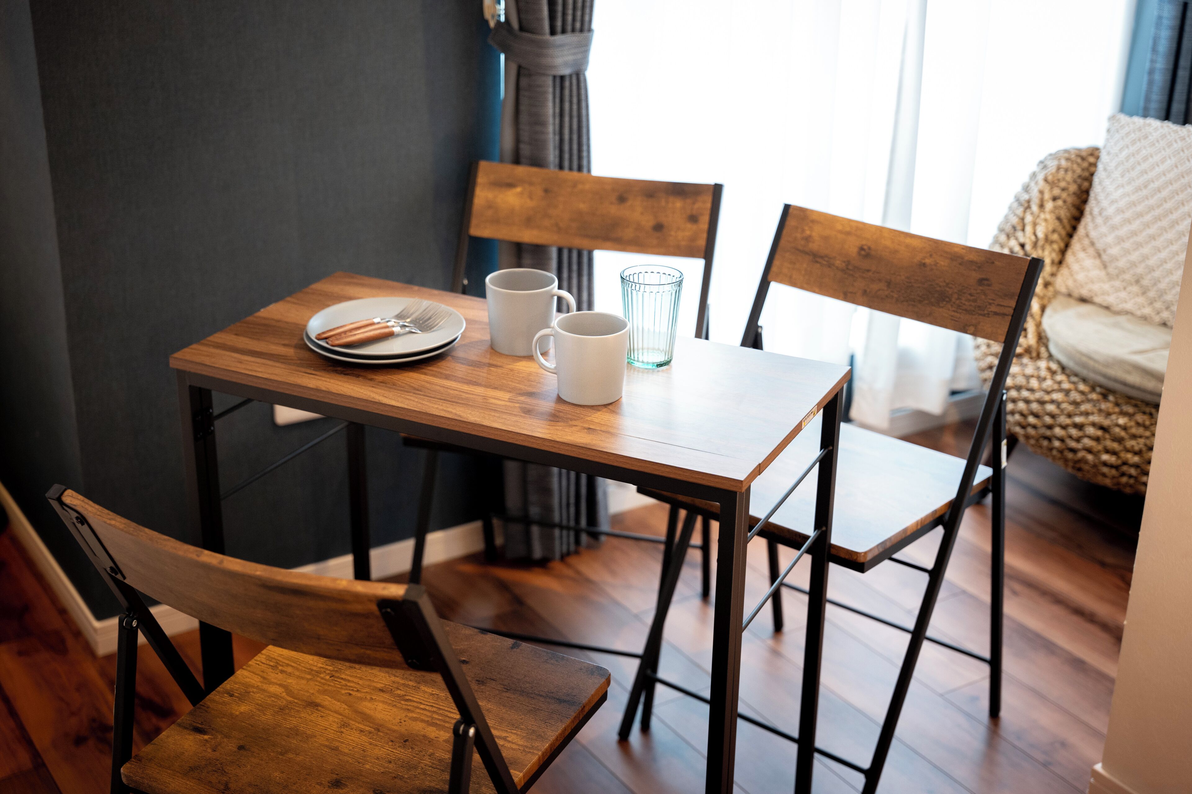 A dining table with chairs, a plate, a fork, a knife, and two cups.