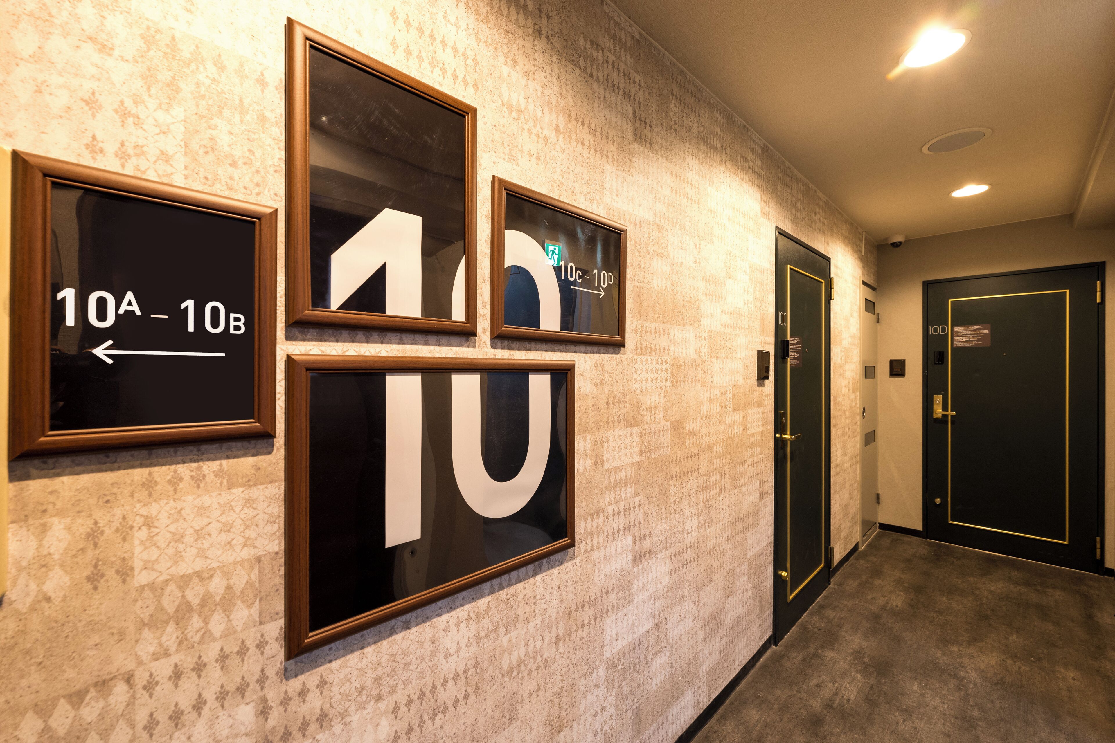 Un couloir avec des panneaux indicateurs et des portes, dont un panneau indiquant la salle 10A-10B.