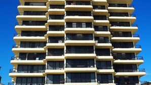 Un immeuble à plusieurs étages doté de balcons, chaque étage ayant une disposition similaire avec des fenêtres et des garde-corps.