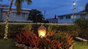 A garden with a large decorative vase, a palm tree, and a bench. - 3 Min Walk to Beach - Blessed Manor (5 Bed House) (Hastings)