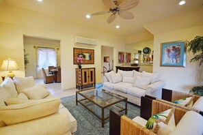 A living room with a sofa, armchairs, a coffee table, and a dining area with chairs and a table.