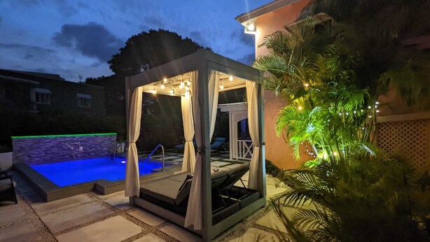 A private outdoor pool area with a covered seating area, a hot tub, and a pergola with string lights. - 3 Min Walk to Beach - Blessed Manor (5 Bed House) (Hastings)