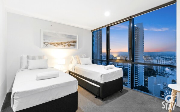 A hotel room with two beds, a large window with a city view, and a painting on the wall. - Circle on Cavill 3 Bedroom Ocean View — Q Stay (Surfers Paradise)
