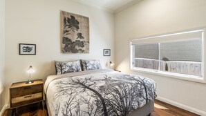 Ein Schlafzimmer mit einem großen Bett, einem Fenster mit Aussicht und zwei Nachttischen mit Lampen.