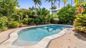 A swimming pool surrounded by tropical vegetation and a building in the background. - Noosaville River Front  - Watch the colors over the water (Noosaville)