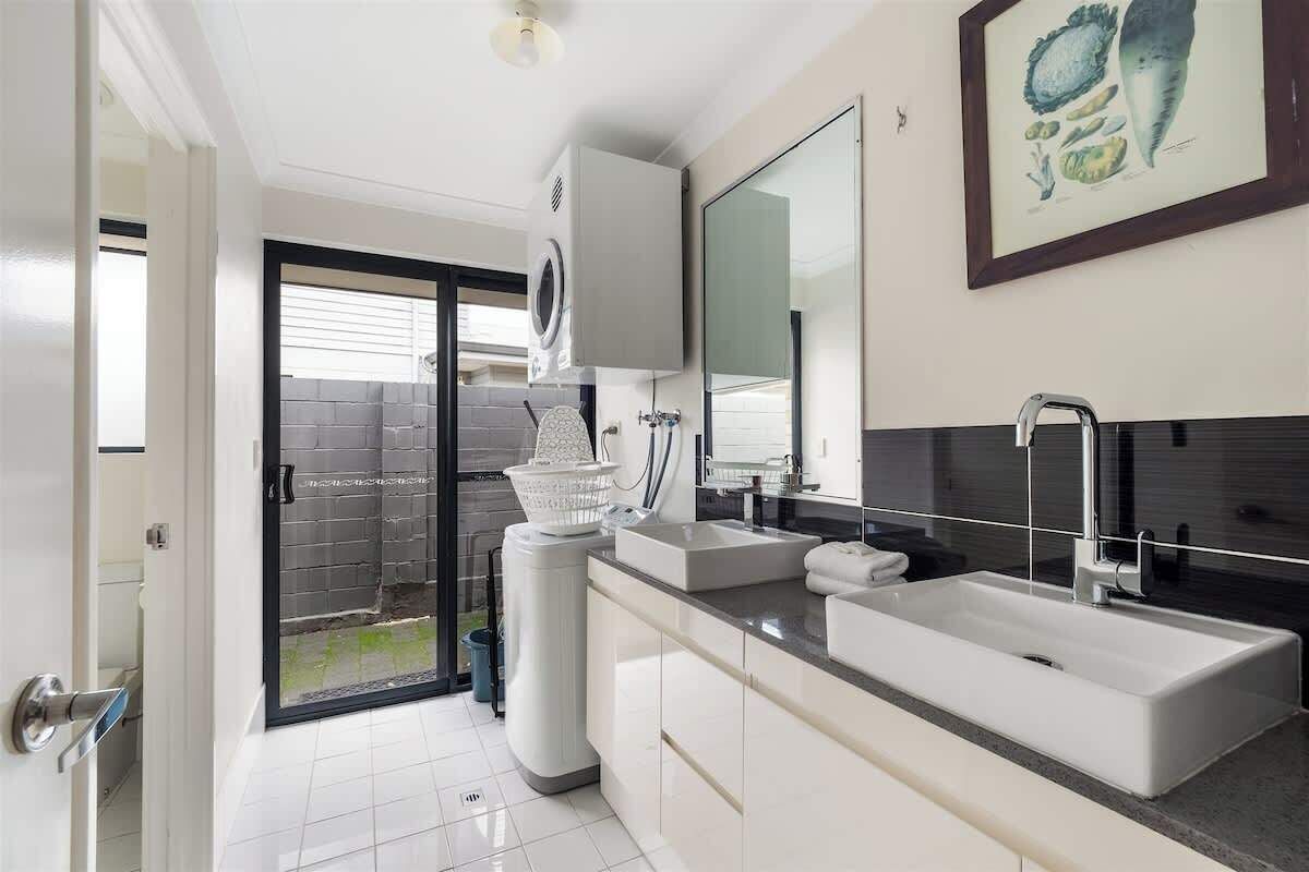 A modern bathroom with a double sink, a large mirror, and a shower area.
