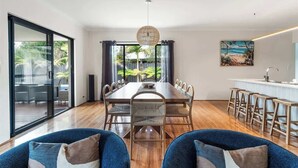 A modern dining area with a long table, chairs, and a view of the outdoors. - Our Escape: Coastal Poolside Haven in Dunsborough (Dunsborough)
