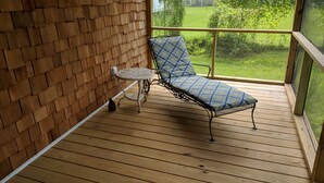 A wooden deck with a metal chair and a small table.