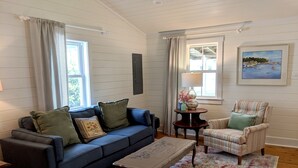 A cozy living room with a blue sofa, a striped armchair, a wooden coffee table, and a patterned rug.