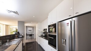 Een moderne keuken met roestvrijstalen apparatuur, een marmeren aanrechtblad en uitzicht op het buiten.