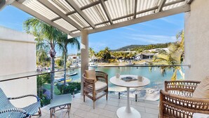 Un balcon agrémenté de meubles en osier, une piscine et une vue sur une zone de villégiature.