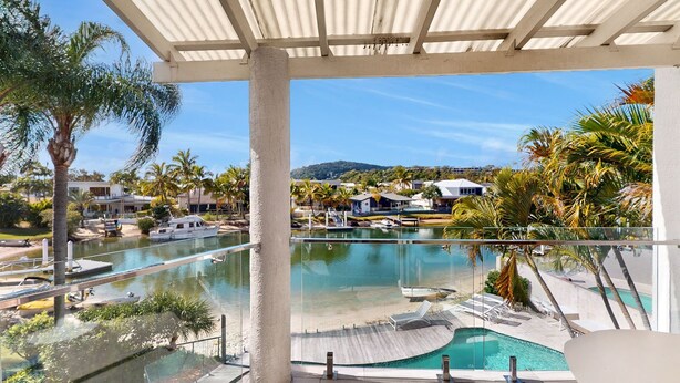 Un espace piscine d’un complexe hôtelier offrant une vue dégagée sur le paysage environnant, notamment sur les palmiers et un bâtiment situé au loin.