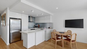 Une cuisine moderne dotée d’un îlot central, d’appareils électroménagers en acier inoxydable et d’un coin repas avec des chaises en bois.