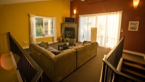 A living room with a sofa, a fireplace, and a television. - Crooked Tree Guest Suites - The Fir Suite (Penticton)