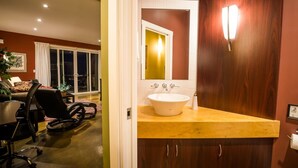 A modern bathroom with a large sink, wooden cabinets, and a mirror. - Crooked Tree Guest Suites - The Fir Suite (Penticton)