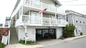 Un edificio a due piani con un balcone, una bandiera e un cartello con su scritto '12 G St. Colonial Sea Side'.