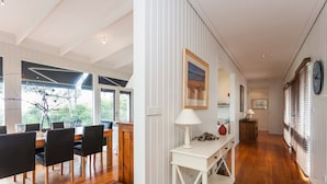 A modern interior with a dining area, a white console table, and a hallway with wooden flooring and white walls. - The Grove (Lorne)