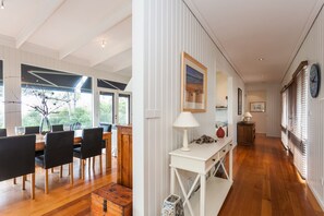 A modern interior with a dining area, a white console table, and a hallway with wooden flooring and white walls.