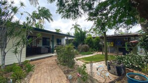 A house with a paved patio, a swan sculpture, and a sign for a beach cafe. - The Batch - Burrum Heads - Walk To Beach - 2BR - Pets Welcome (BURRUM HEADS)