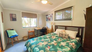 A bedroom with a bed, desk, chair, and two windows. - The Batch - Burrum Heads - Walk To Beach - 2BR - Pets Welcome (BURRUM HEADS)