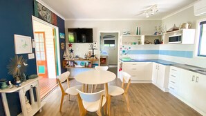 A modern kitchen with white cabinets, a round dining table, and wooden chairs. - The Batch - Burrum Heads - Walk To Beach - 2BR - Pets Welcome (BURRUM HEADS)