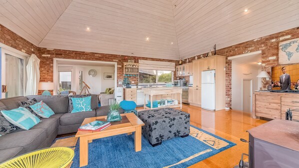A spacious living area with a sofa, coffee table, and a kitchen in the background.