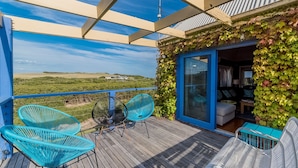 A covered outdoor deck with blue chairs, a table, and a view of the countryside. - Mills Court, Quirky seaside house at Smiths Beach, bring the surf boards! (Smiths Beach)