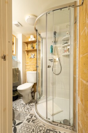 Un baño moderno con ducha de vidrio, inodoro y suelo estampado.