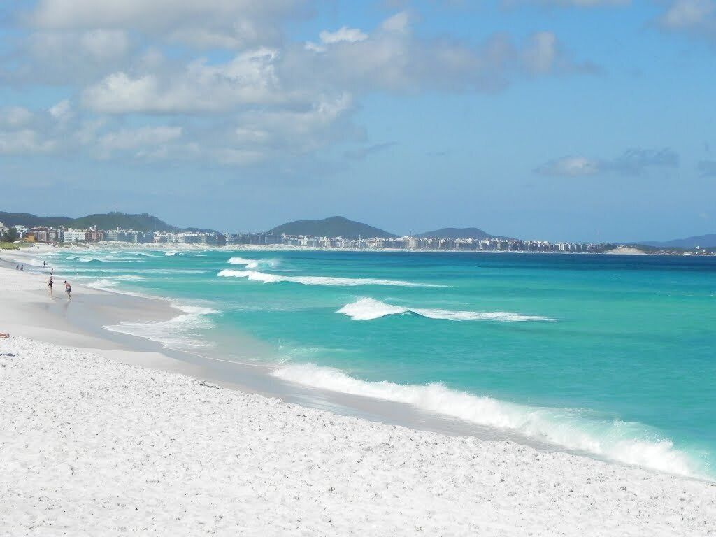 A beach with white sand and turquoise water.