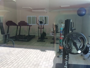 A gym with treadmills, a stationary bike, a rowing machine, and a weight rack.