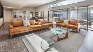 A modern living room with a large sofa set, a glass coffee table, and a view of the outside. - Mimosa—Stylish Beachside Retreat in Dunsborough (Dunsborough)