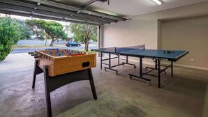 A garage with a foosball table, ping pong table, and a carport door. - Mimosa—Stylish Beachside Retreat in Dunsborough (Dunsborough)