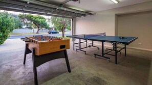 Un garaje con mesa de fútbol de mesa, mesa de ping pong y puerta de cochera.