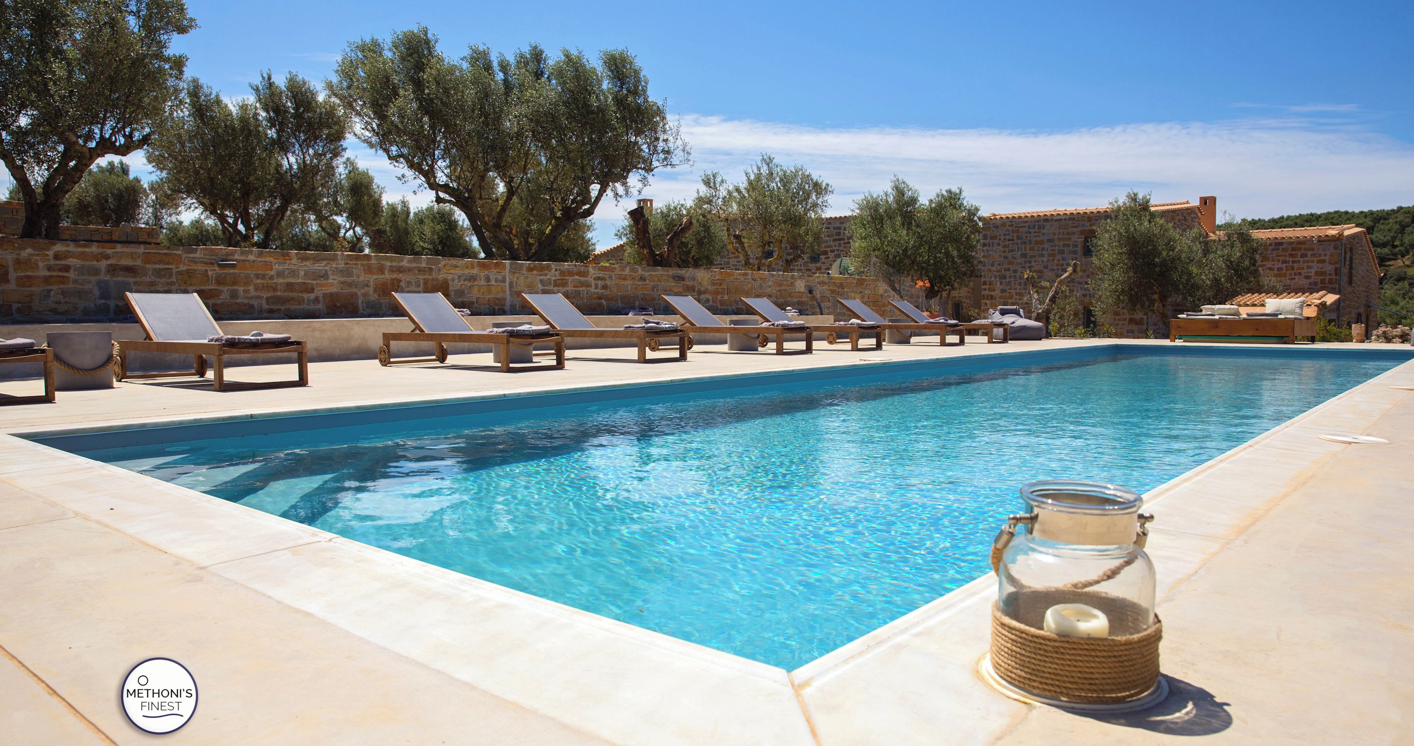 Una piscina con sillones de descanso y un tarro de vidrio en el borde.