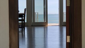 A room with a view of the sea through large glass doors.