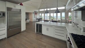A modern kitchen with a large island, stainless steel appliances, and a view to the outdoors.
