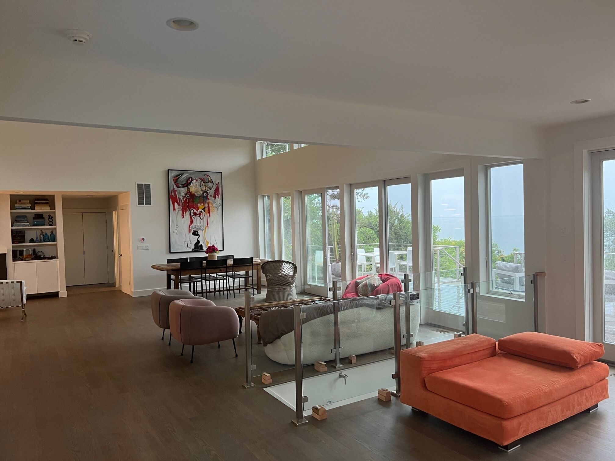 Uma sala de estar espaçosa, com uma grande janela, área de jantar com mesa e cadeiras, e um sofá.