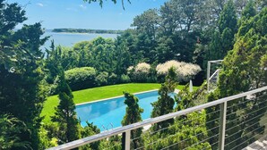 A pool surrounded by lush greenery and a clear view of the sea.