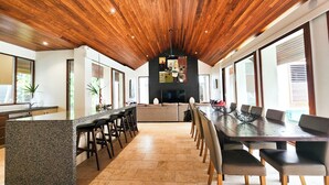 A modern kitchen with a central island, bar stools, and a dining area with a long table and chairs.